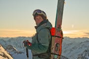 Eine Person im Winter in den Bergen, sie hat die Tourenski am Rucksack befestigt.