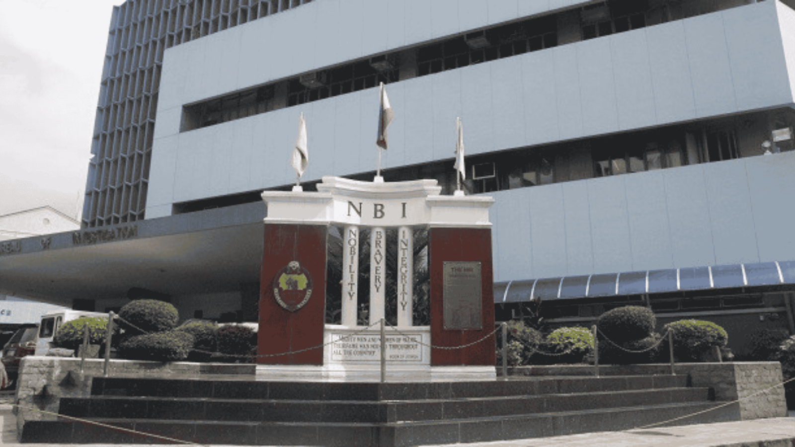Monument displaying the values of Nobility, Bravery, and Integrity in front of a modern government building.