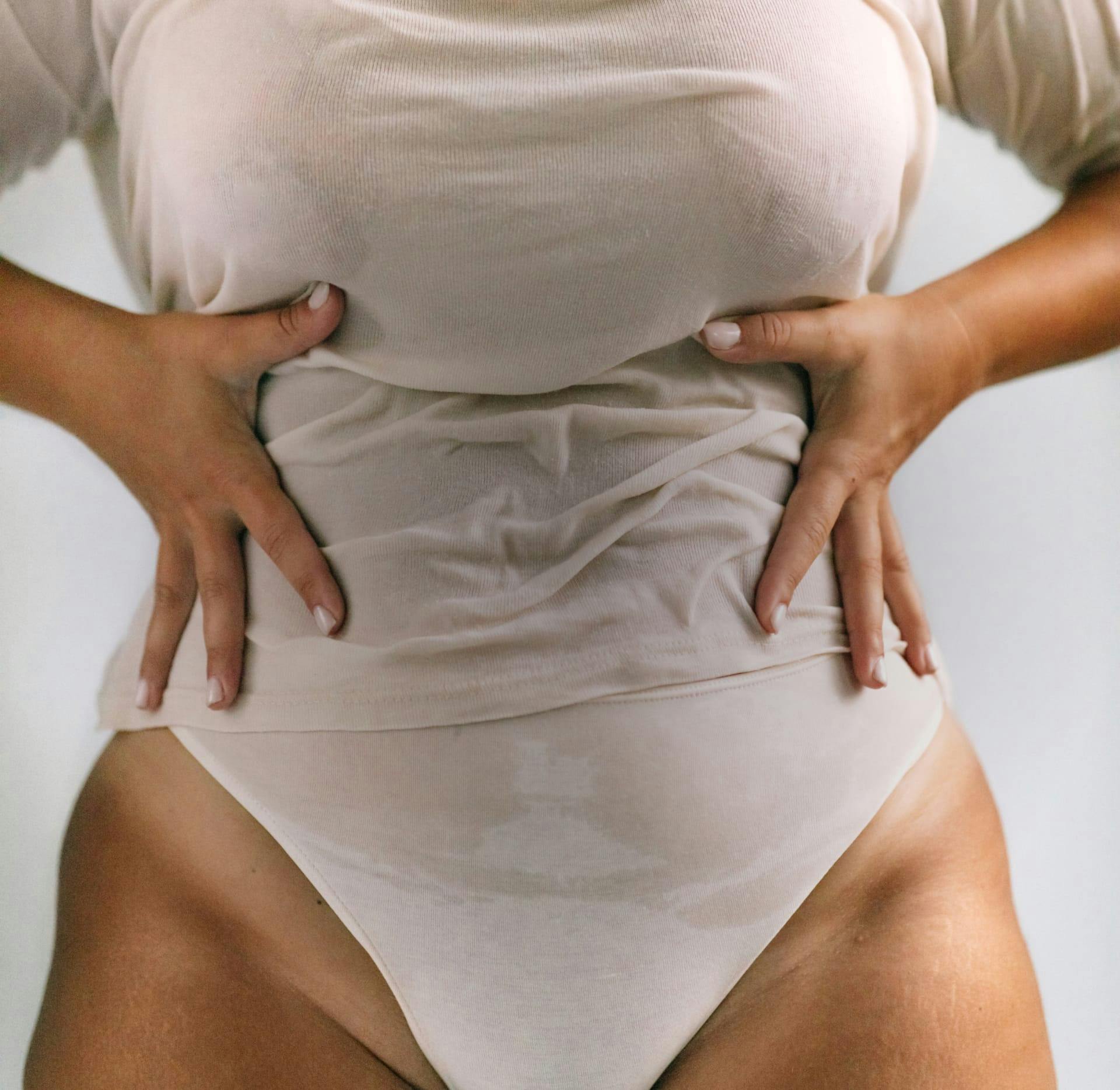 Mid-section of a woman with her hands to her stomach