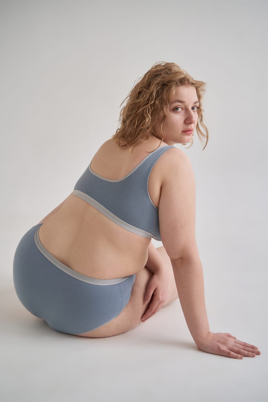 Woman in her underwear, sitting down and looking backwards