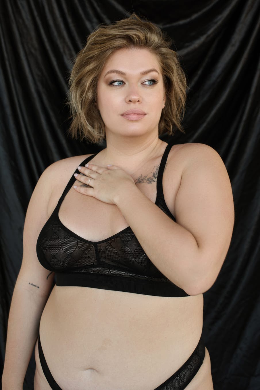 Woman in her underwear with a hand to her chest