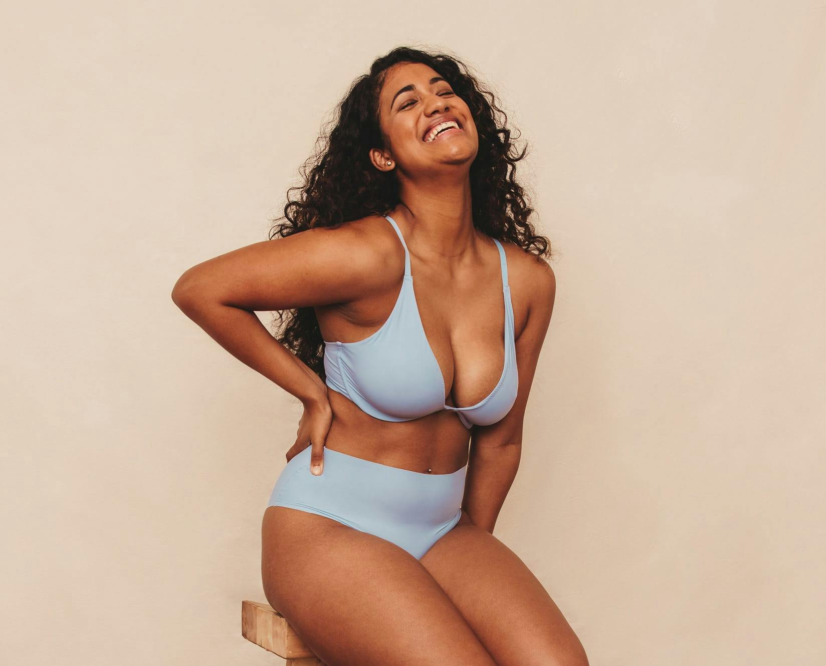 woman in blue underwear sitting on stool with one hand on waist