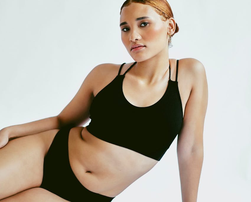 woman laying on her side, with hand holding her up and the other laying on her thigh