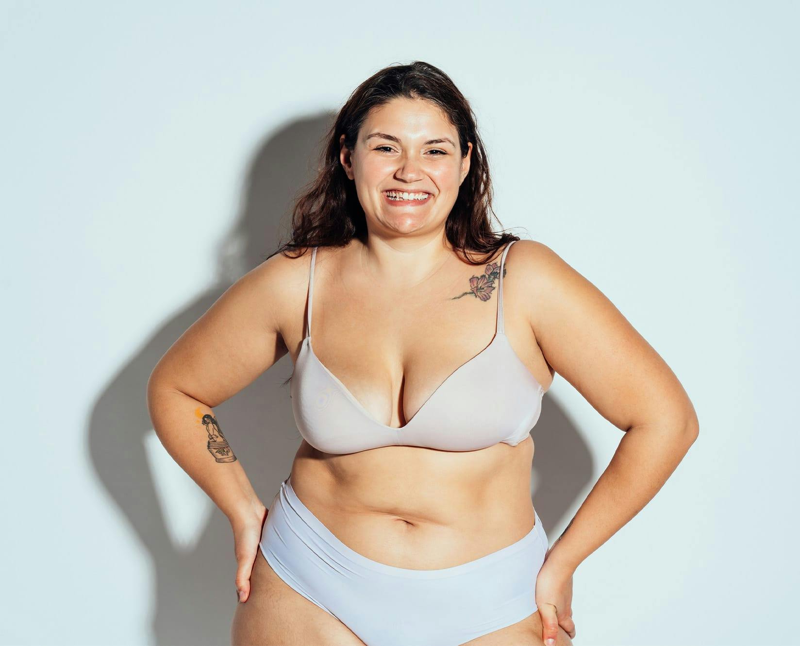 plus size woman in white underwear, with both hands on hips smiling