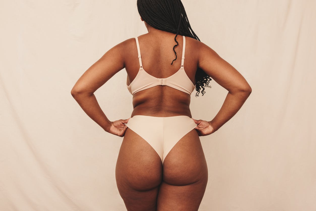 The back of a black woman in her bra and underwear in a studio shoot