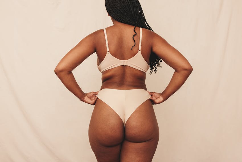 The back of a black woman in her bra and underwear in a studio shoot
