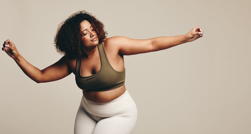 Curvy woman arms up, dancing in studio shoot