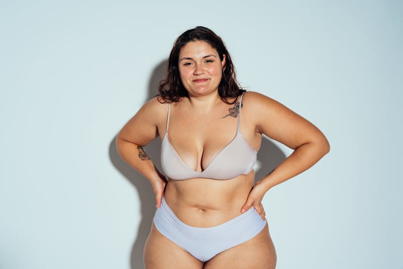 Plus size woman smiling in bra and underwear in studio shoot
