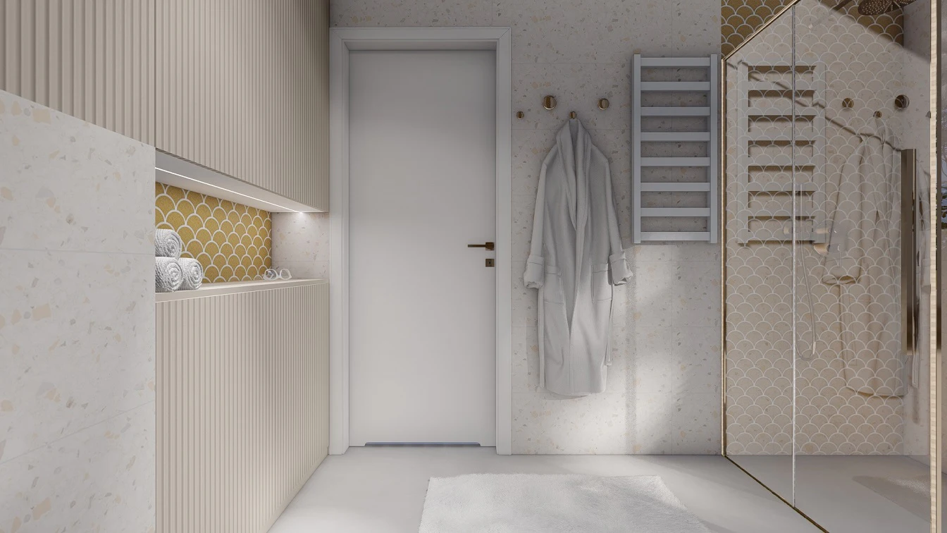 Ściana z prysznicem w złotym okuciu. Grzejnik naścienny w białym macie oraz okrągłe, złote wieszaki na ręczniki i szlafroki.