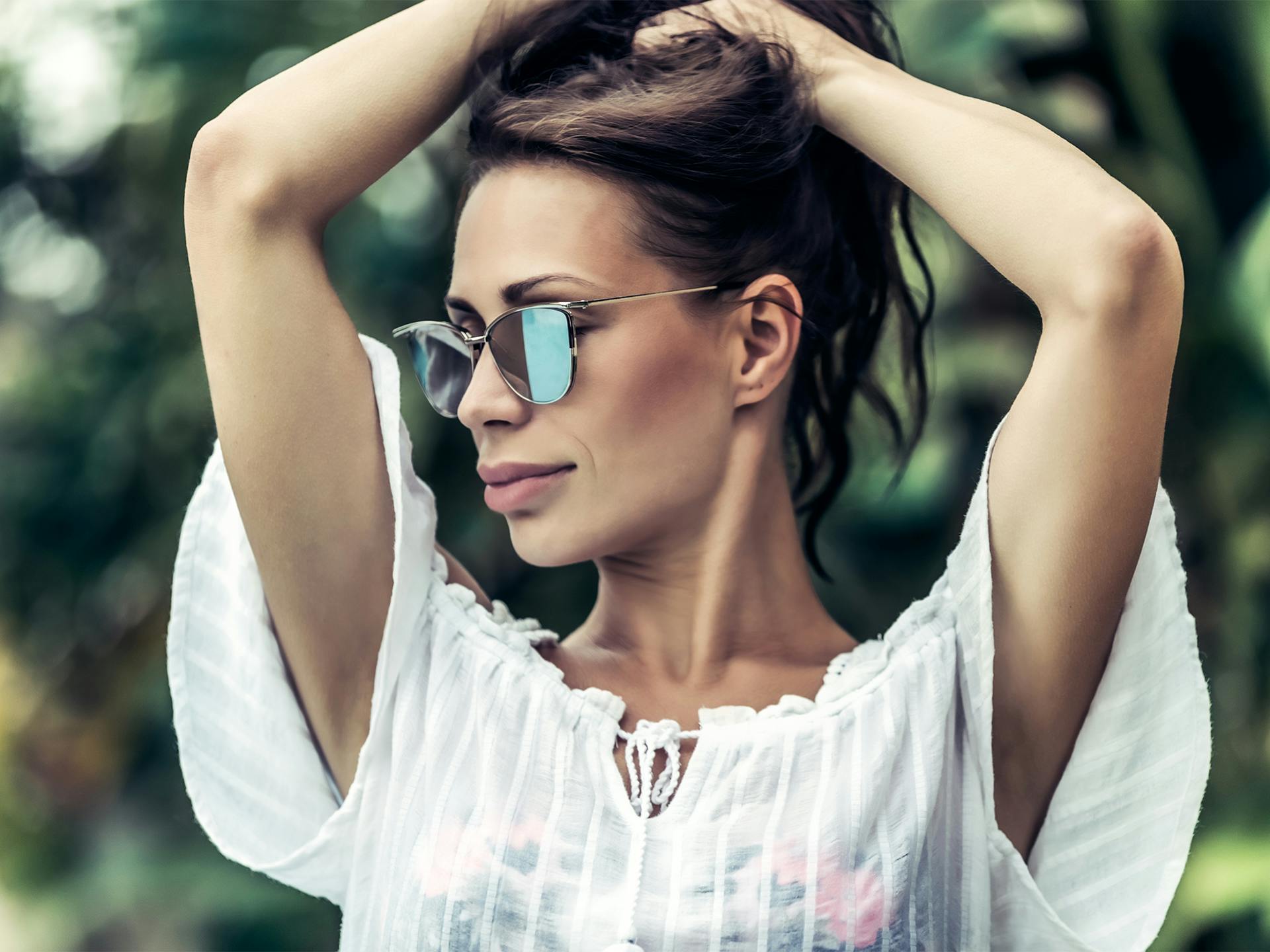 Woman in sunglasses wearing white blouse.