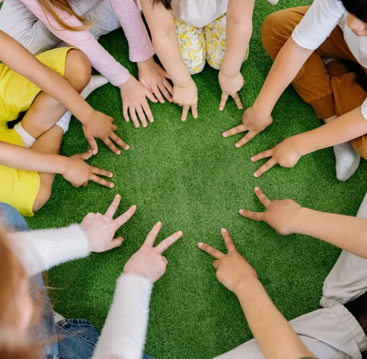 Many kids with hands in the middle of a circle