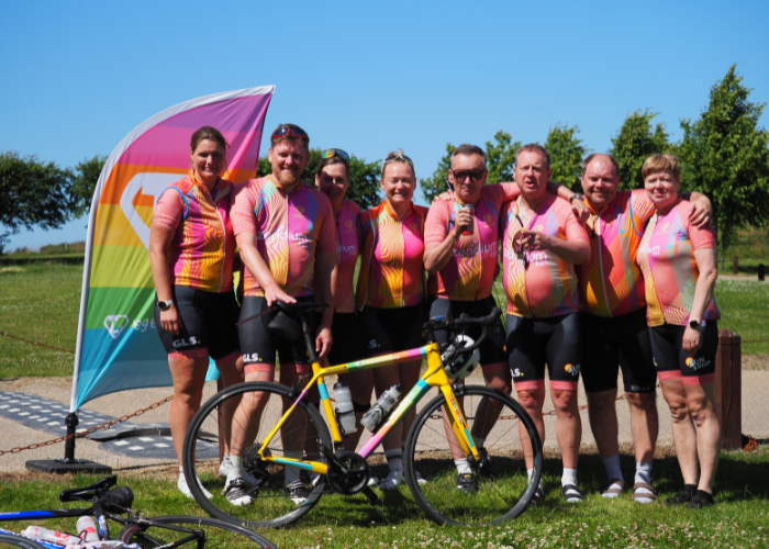 Holdfoto af cykelryttere med cykel foran og helte-beachflag