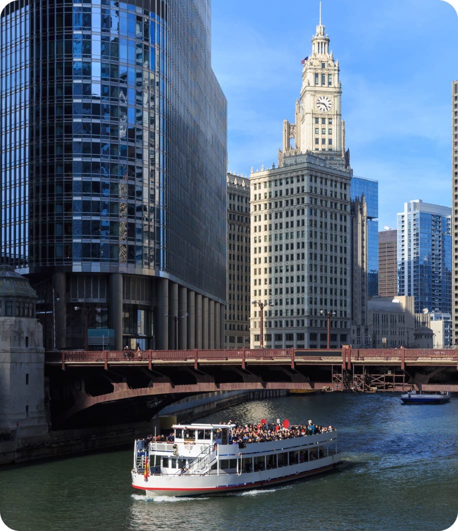 Photo of Boat traveling down river under bridge surrounded by tall buildings