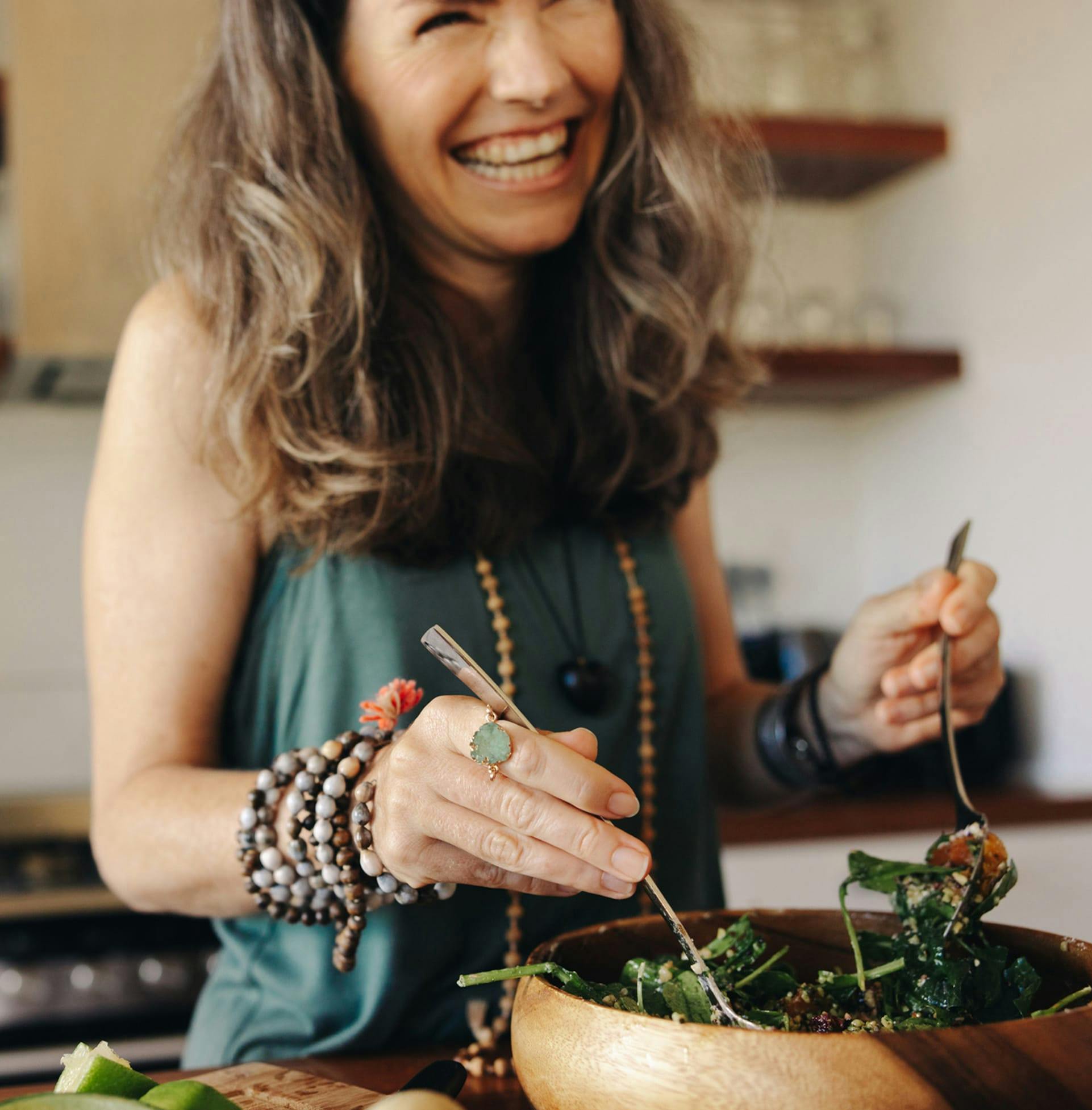 woman smiling and mixing salad