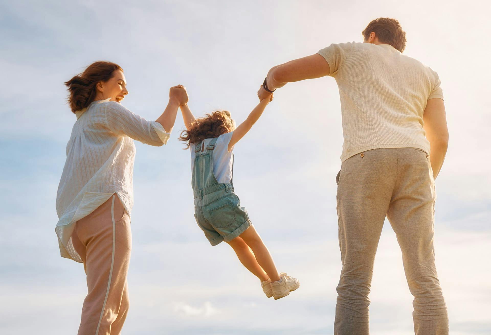 Parents smiling and lifting Daughter by her arms