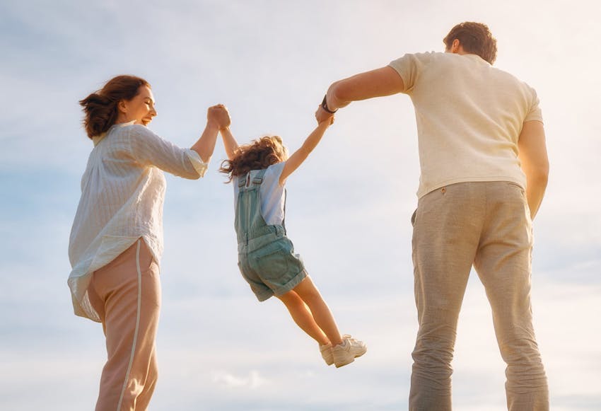 Parents smiling and lifting Daughter by her arms