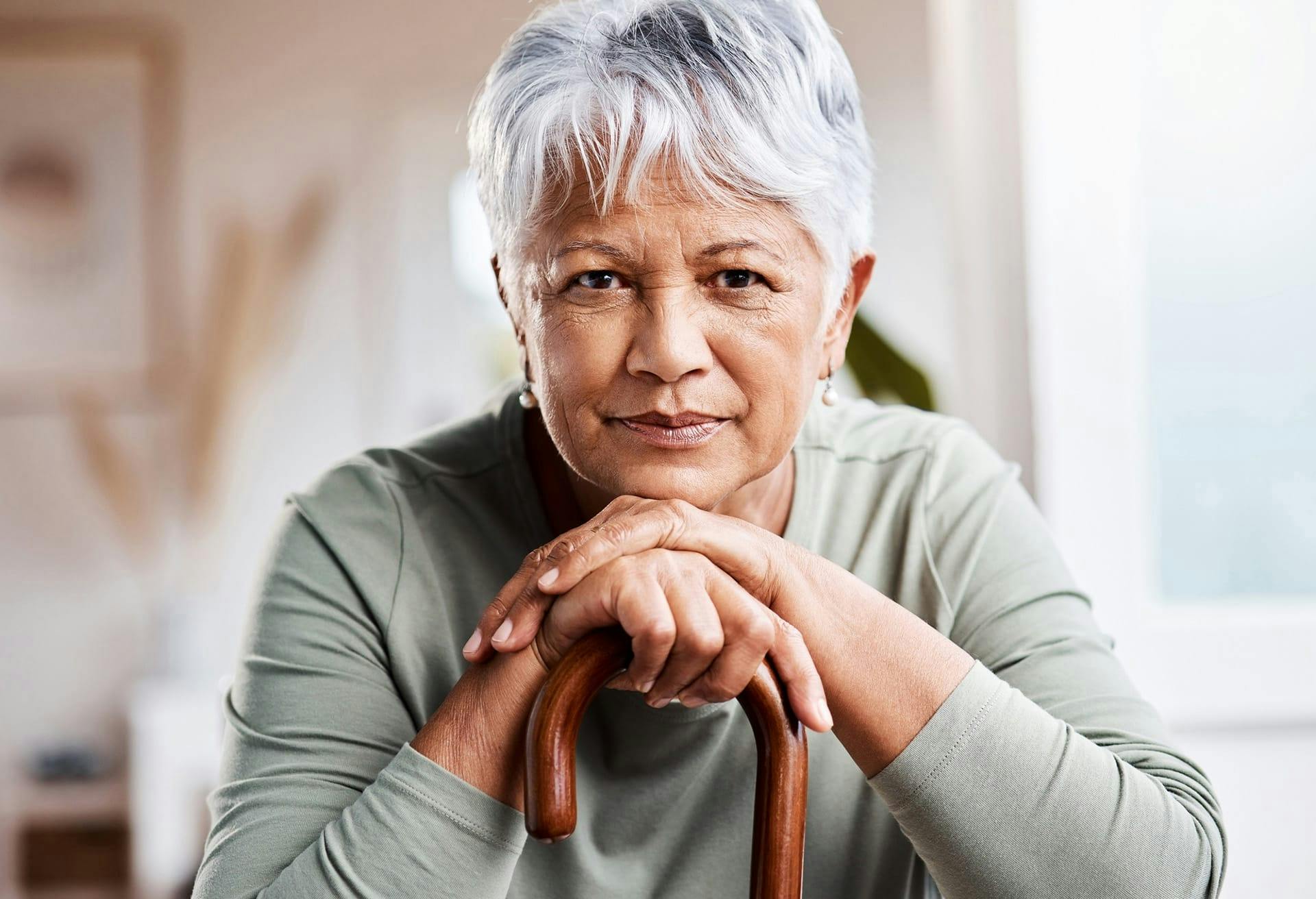 Woman looking straight ahead chin resting on cane