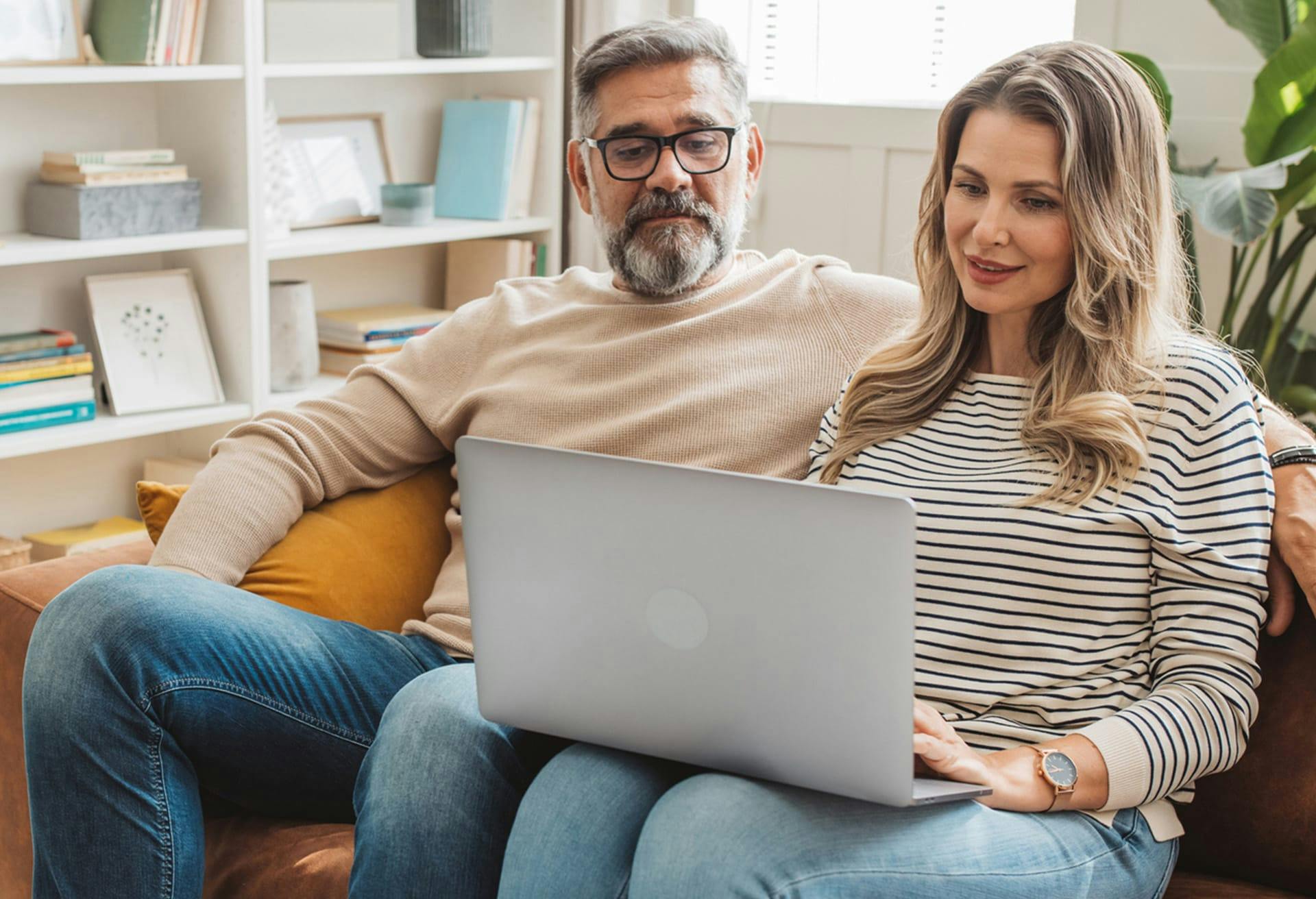 couple sitting on couch looking at laptop