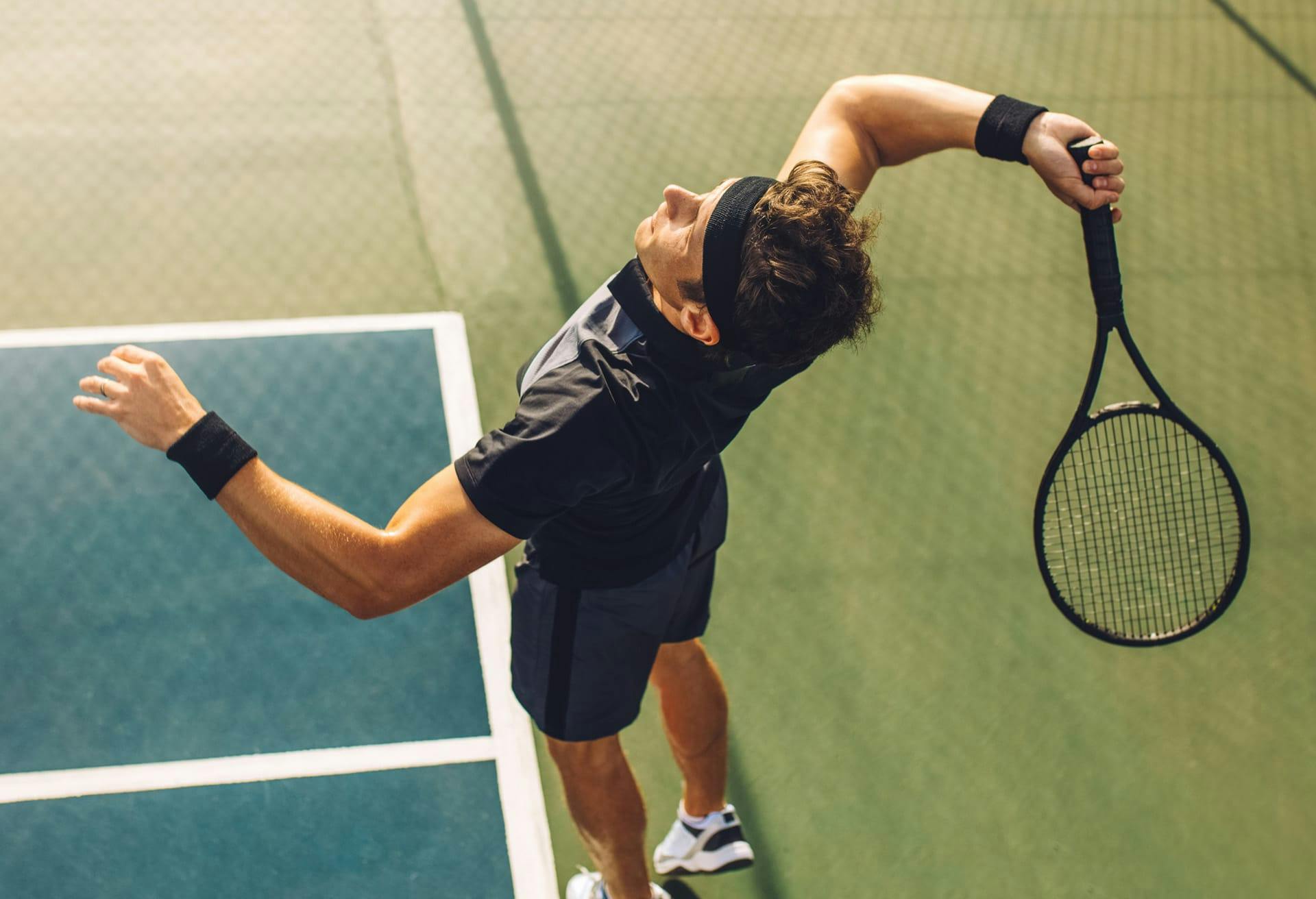 Man jumping up with tennis racket about to hit tennis ball