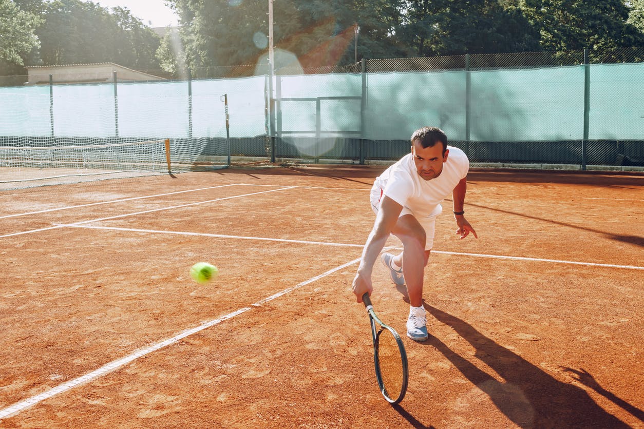 Man playing tennis swings upward showcasing his elbow mobility