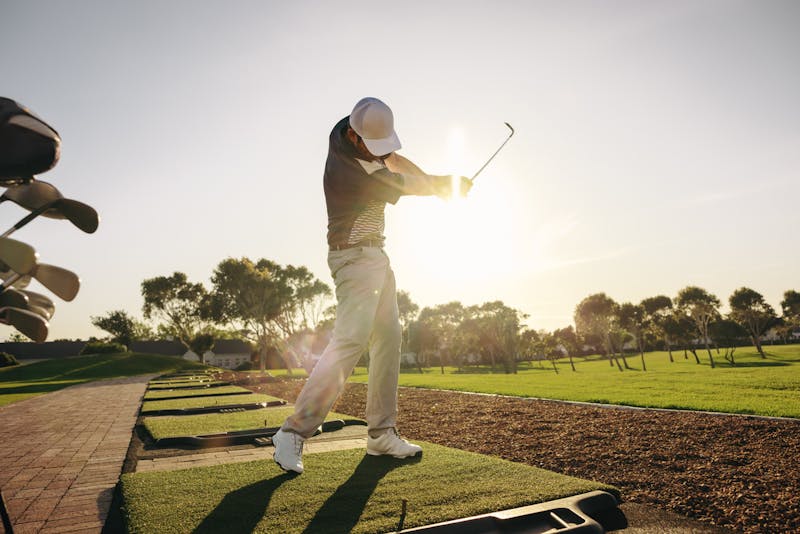 Golfer swinging his clubs on the green