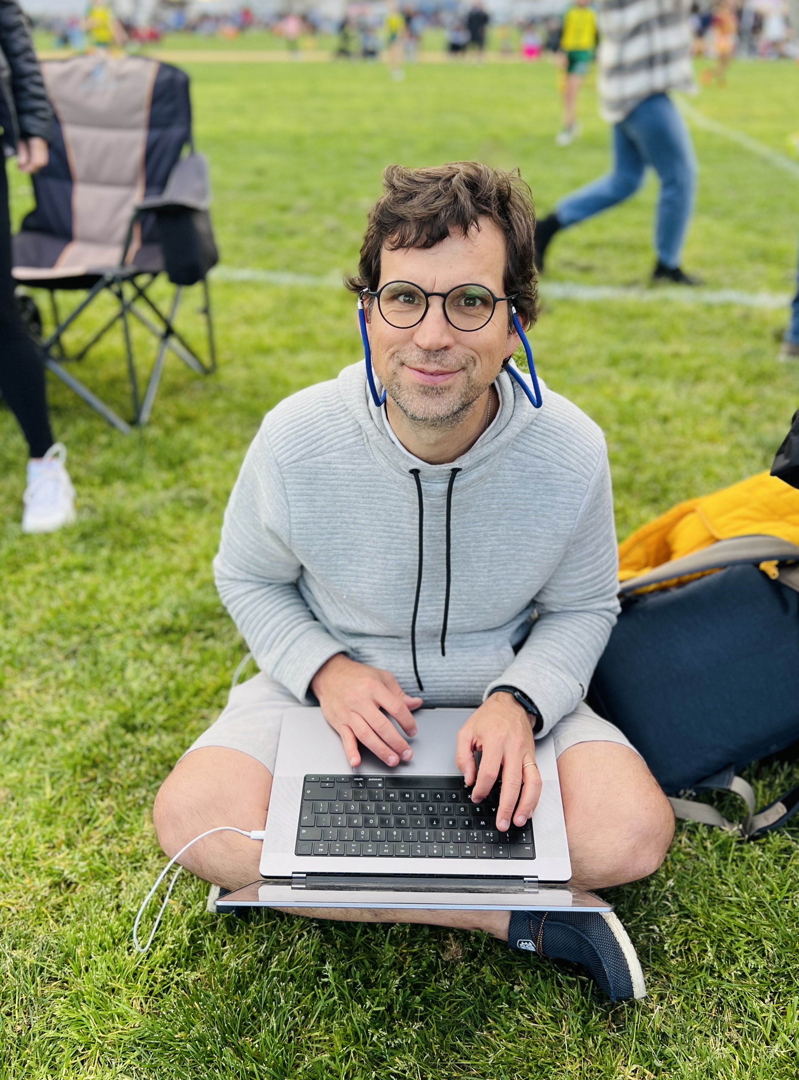 Img: grass, person, sitting, laptop, pc, adult, male, man, glasses, jeans