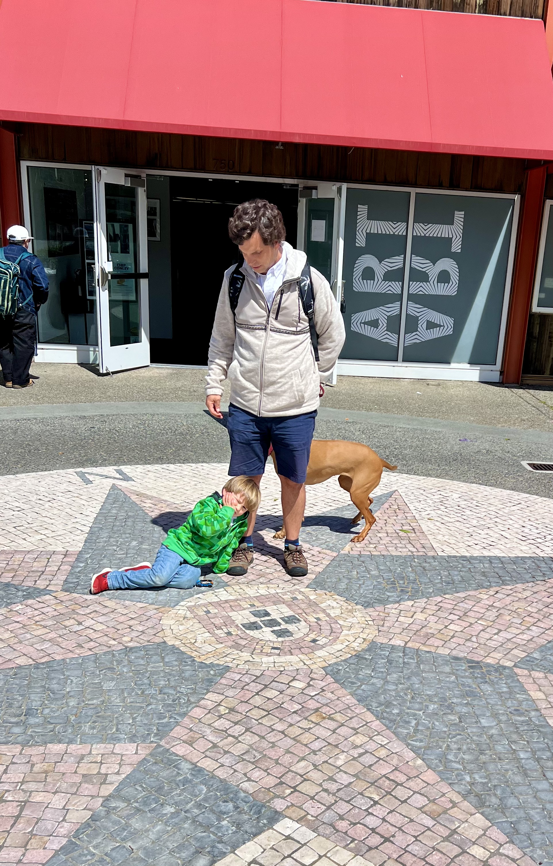 Img: path, shorts, city, street, pants, shelter, backpack, person, portrait, sidewalk