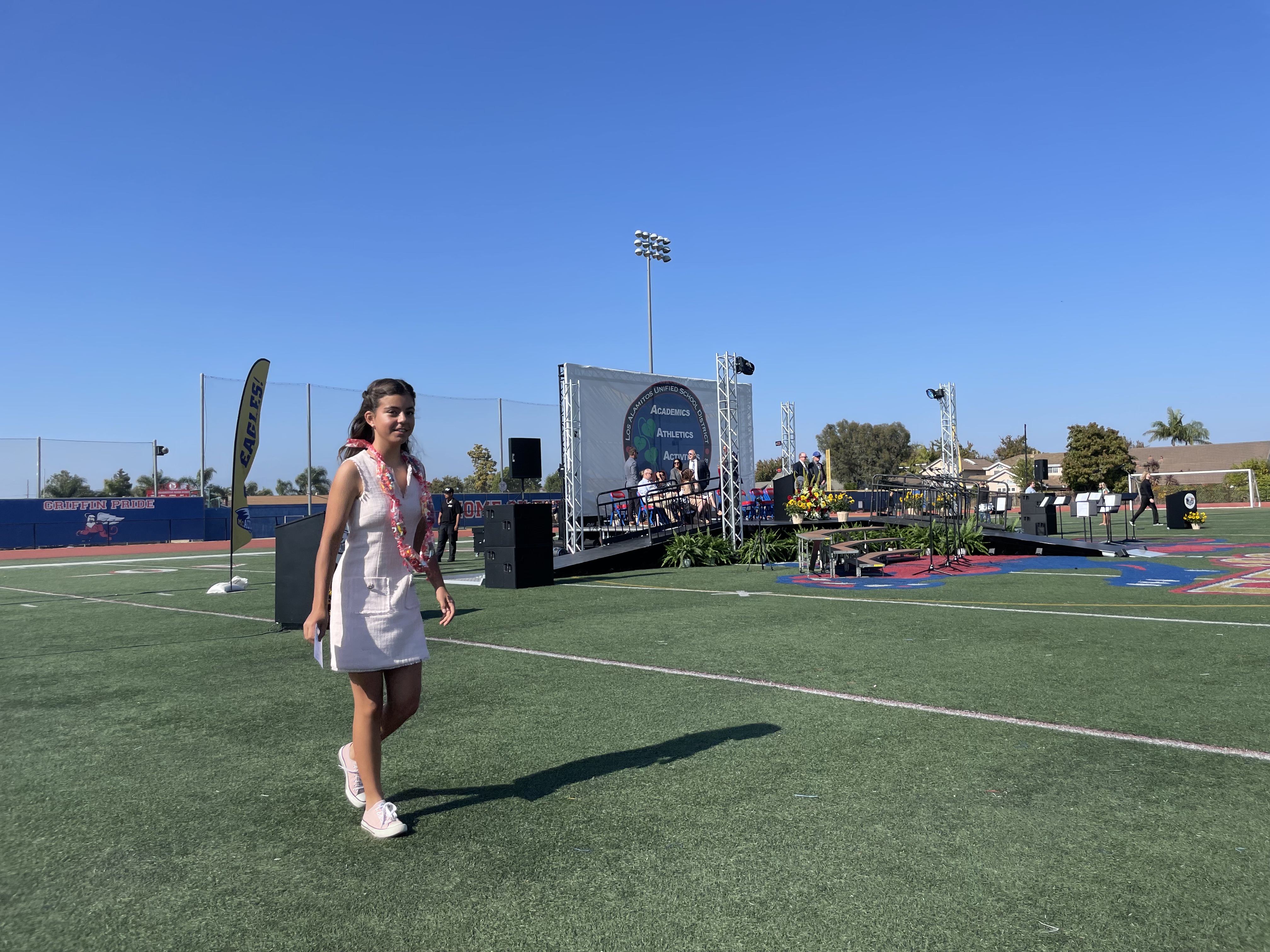 Img: field, speaker, shoe, female, girl, person, teen, people, necklace, standing