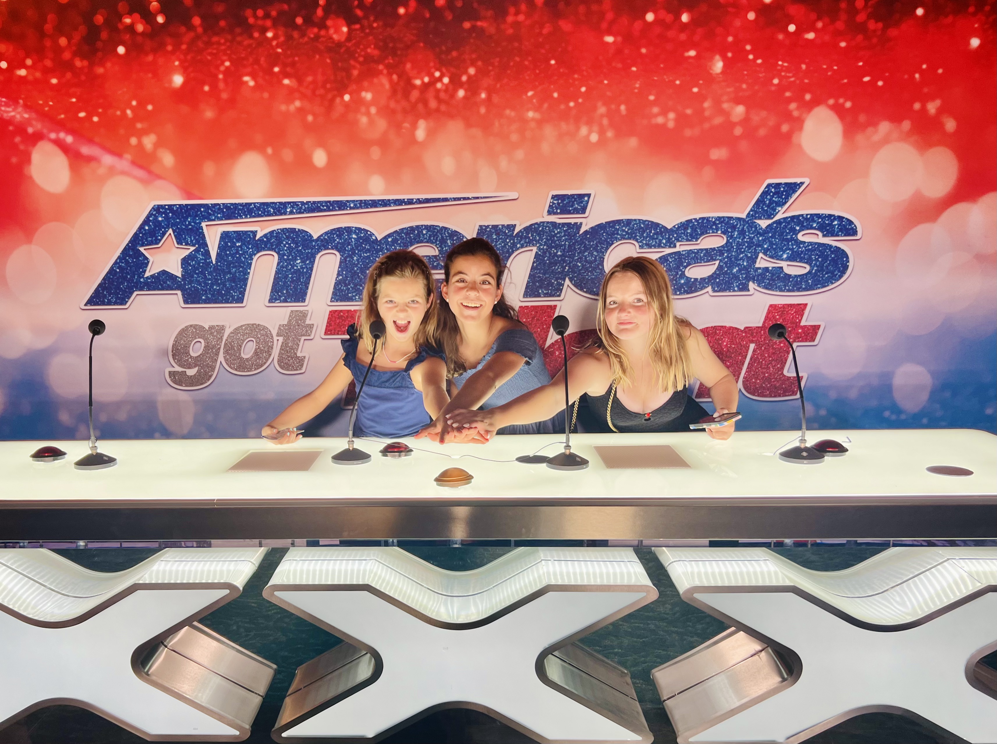 Img: person, electrical device, microphone, jewelry, necklace, child, female, girl, reality show judges panel, mobile phone