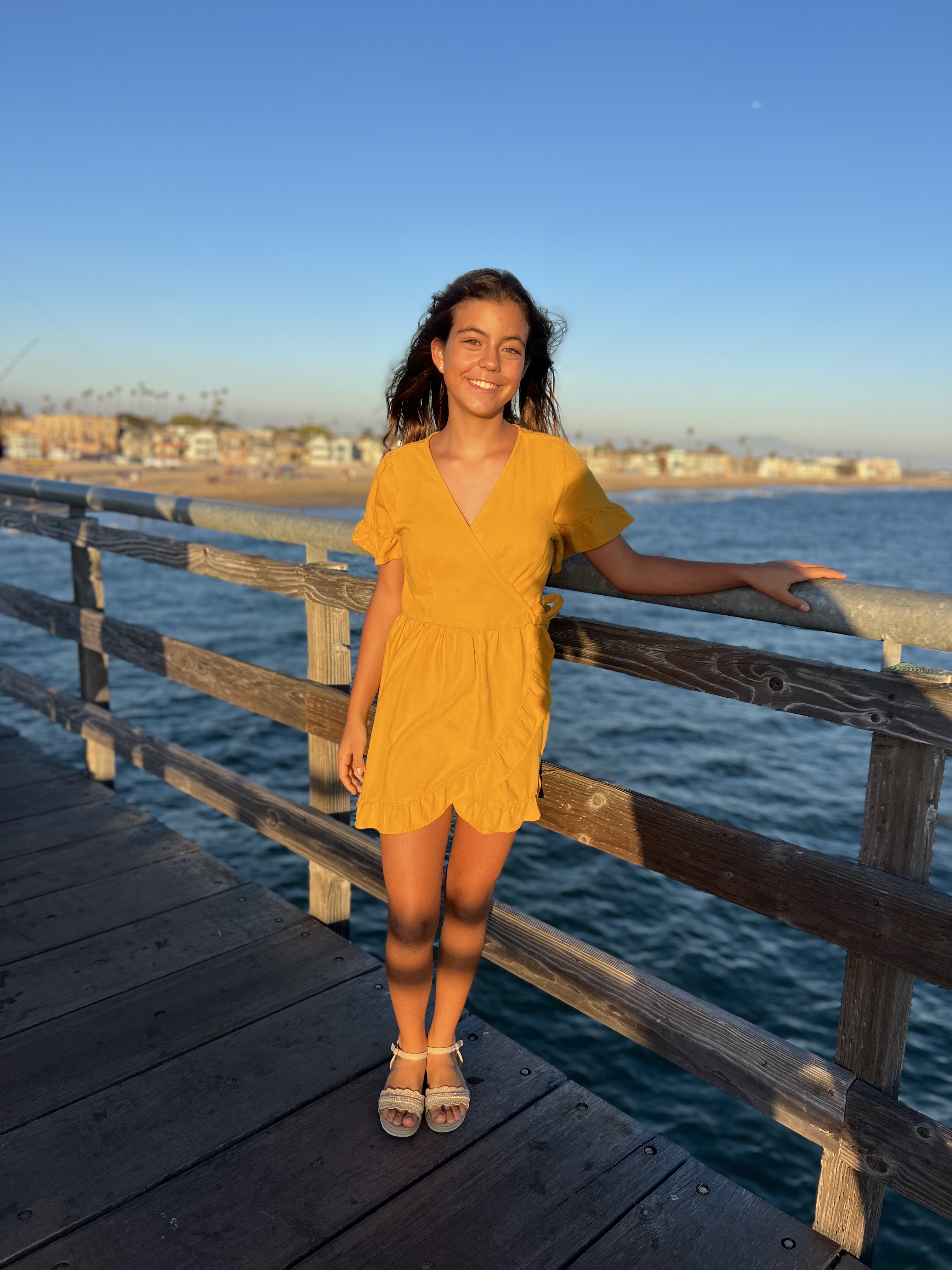 Img: waterfront, dress, pier, handrail, person, boardwalk, sandal, beachwear, smile, sleeve