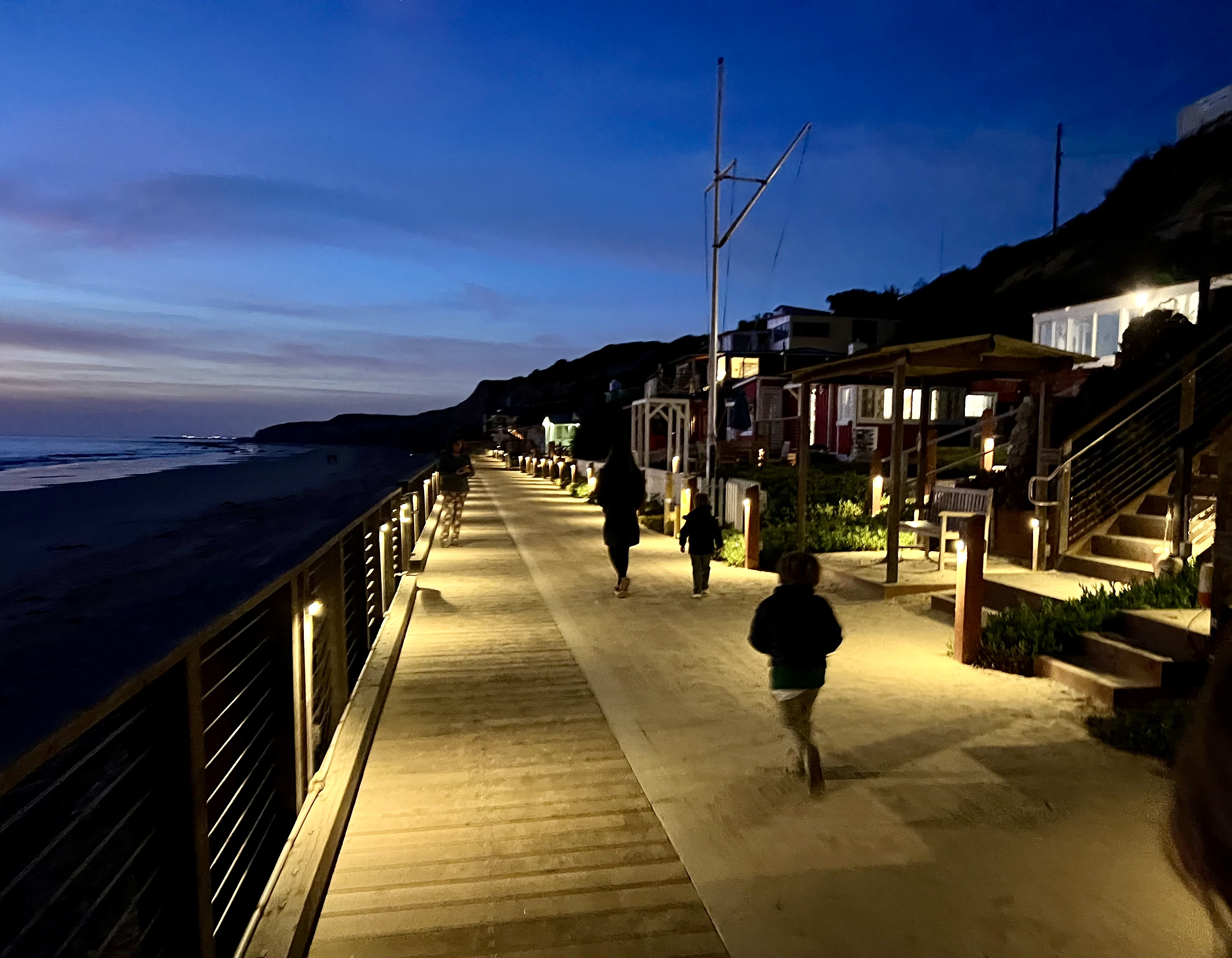 Img: path, sidewalk, water, waterfront, handrail, boardwalk, walkway, person, bench, shoe
