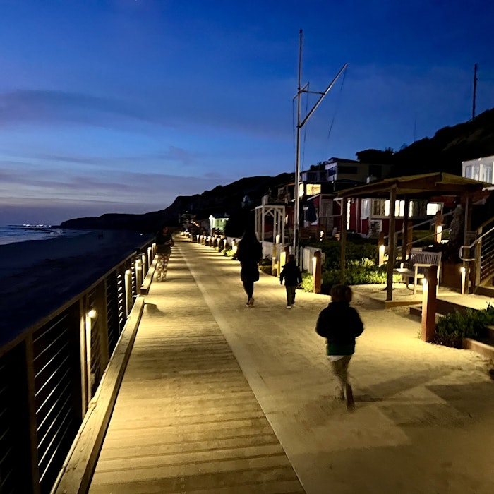 Img: path, sidewalk, water, waterfront, handrail, boardwalk, walkway, person, bench, shoe