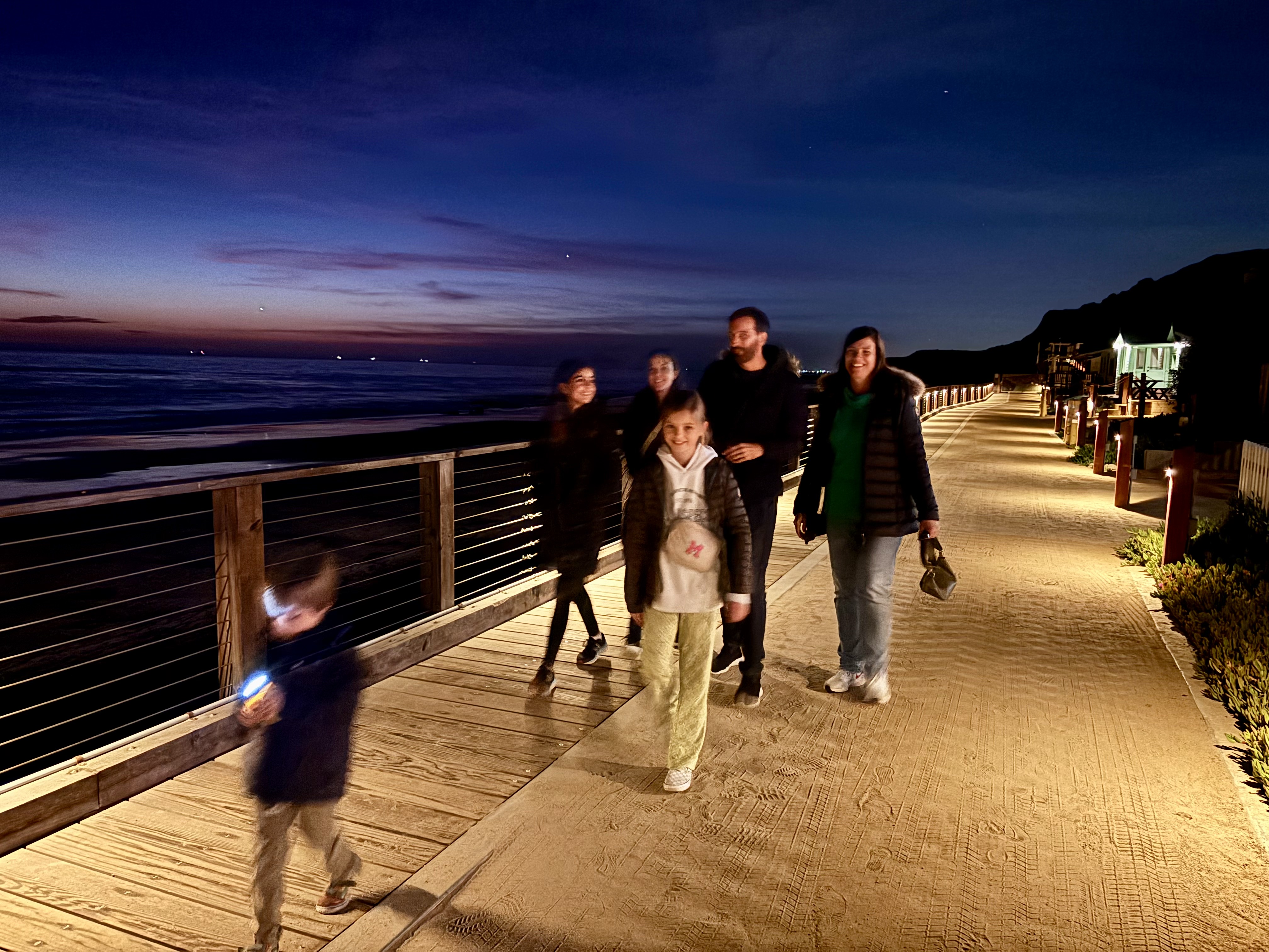Img: person, walking, waterfront, path, sidewalk, boardwalk, pants, walkway, shoe, handbag