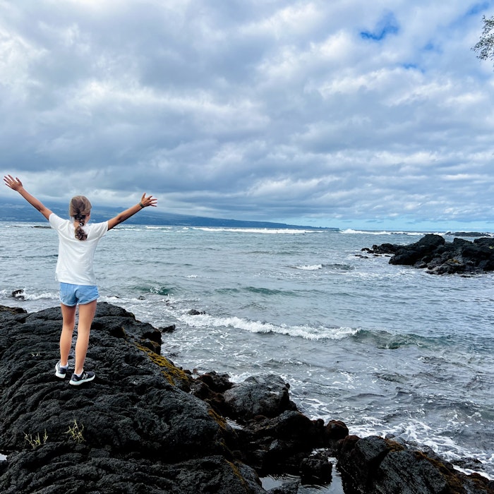 Img: face, happy, head, person, rock, shorts, shoe, triumphant, outdoors, nature
