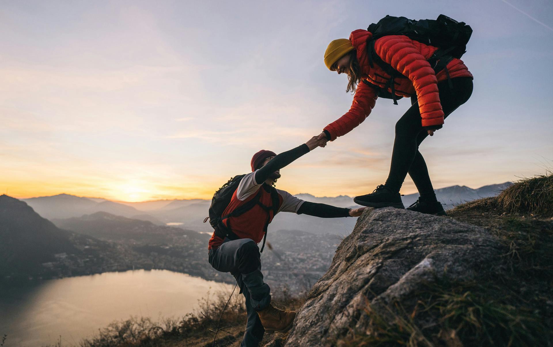 Woman helping man onto rock.