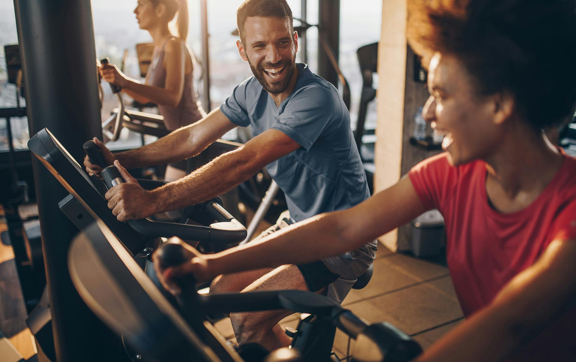 People smiling while using workout bikes.