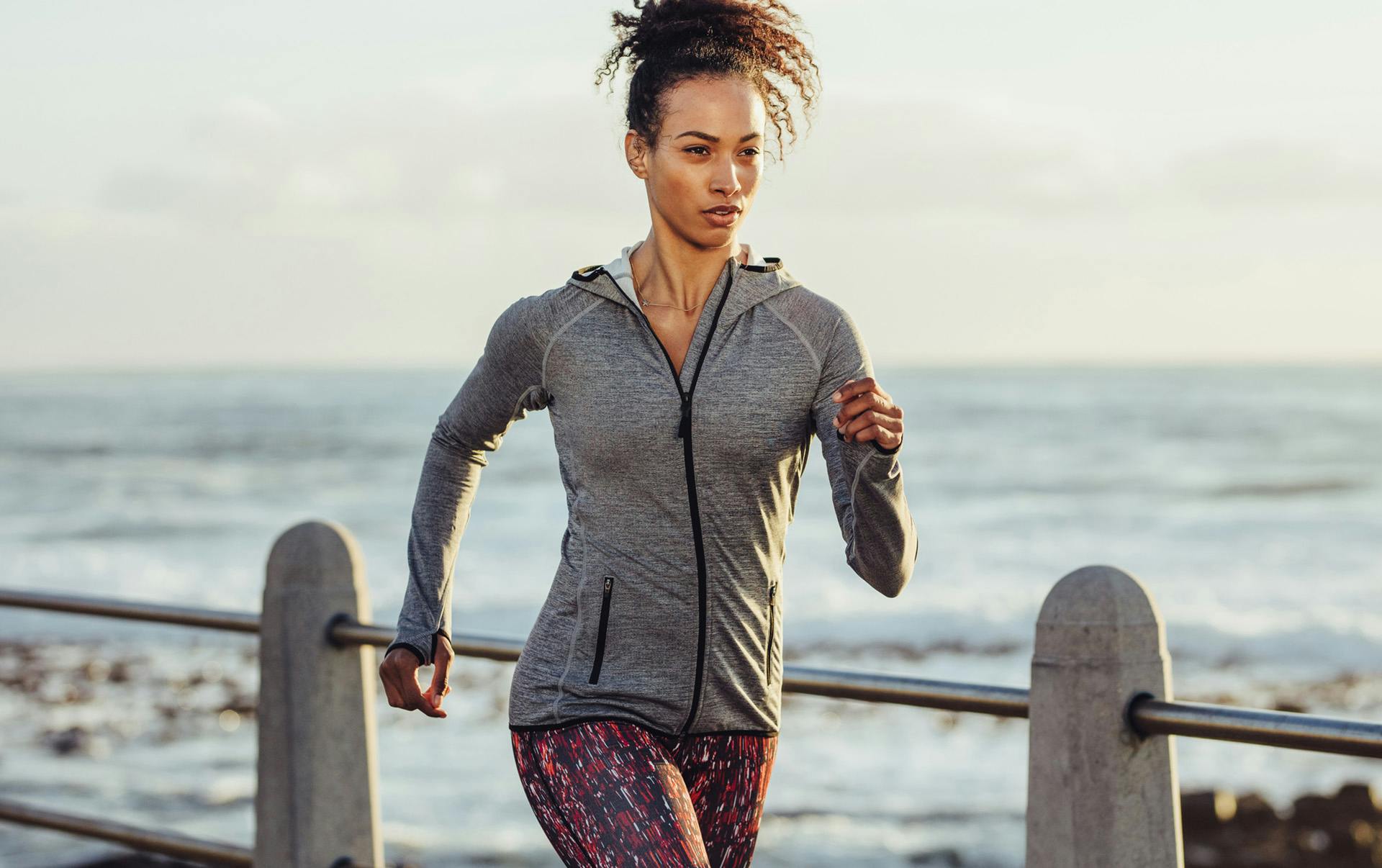 Woman in activewear jogging on jetty.