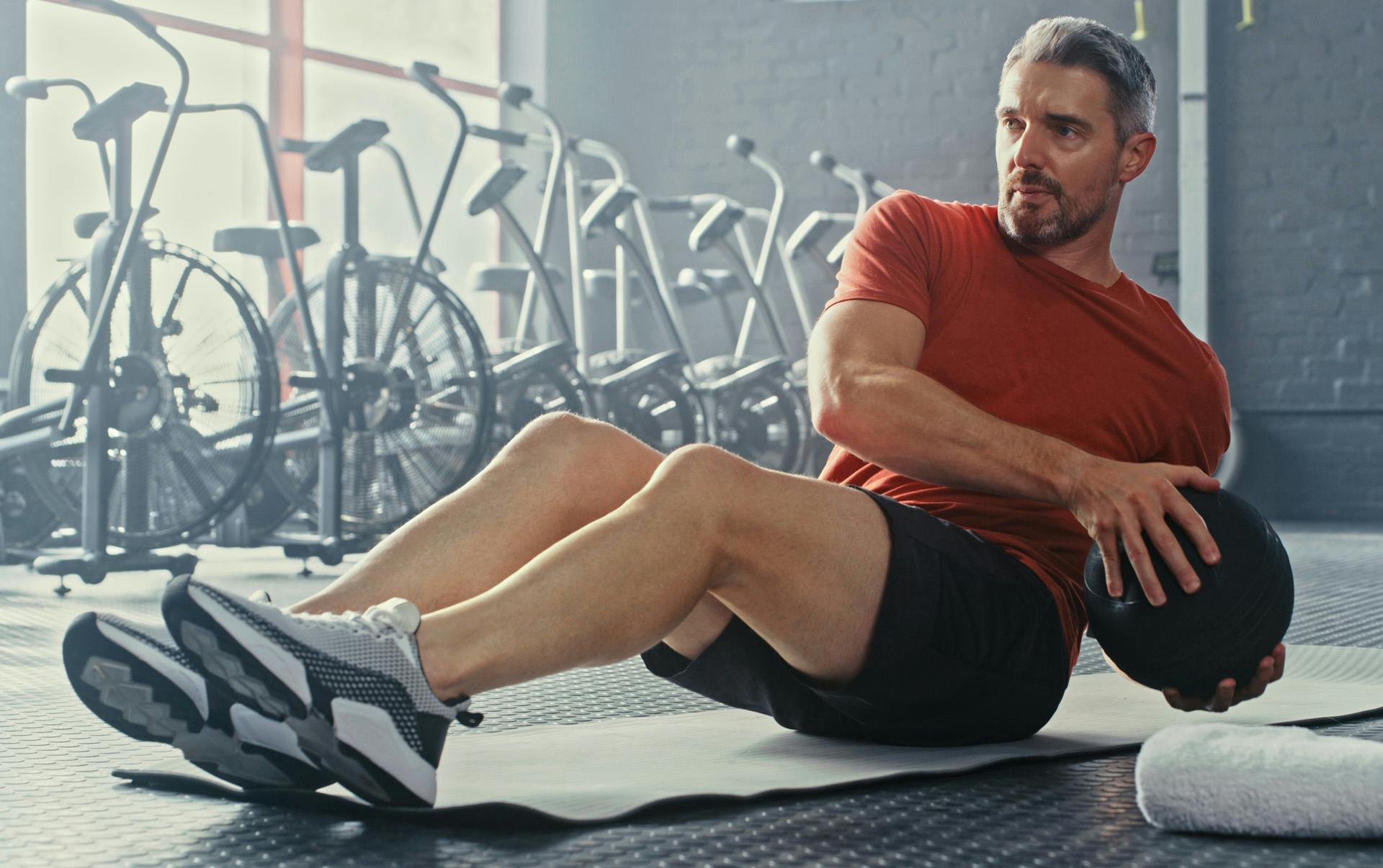 Man in red shirt doing medicine ball workout.