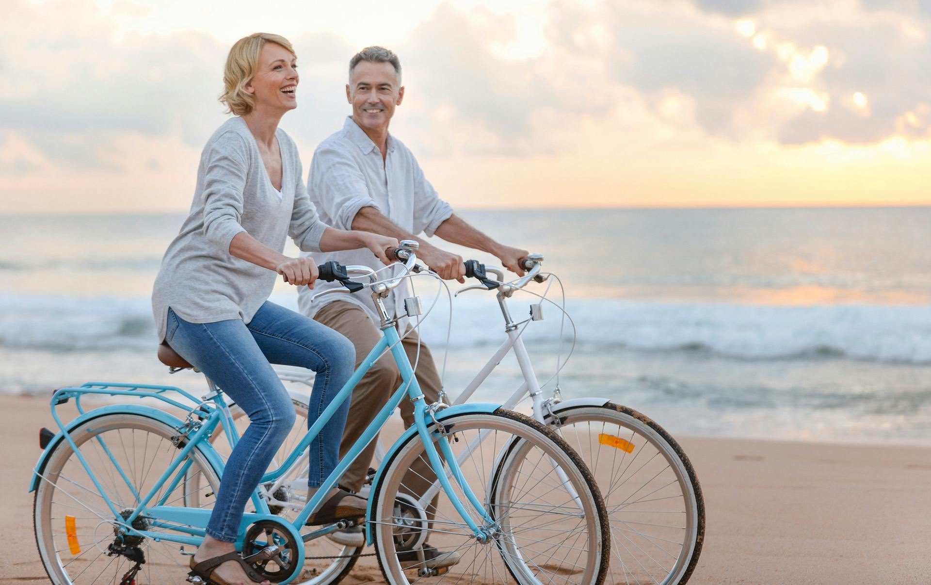 Couple riding bikes on beach.