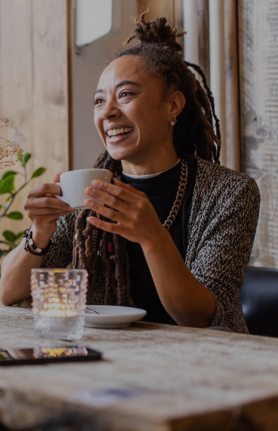 woman laughing while holding a cup