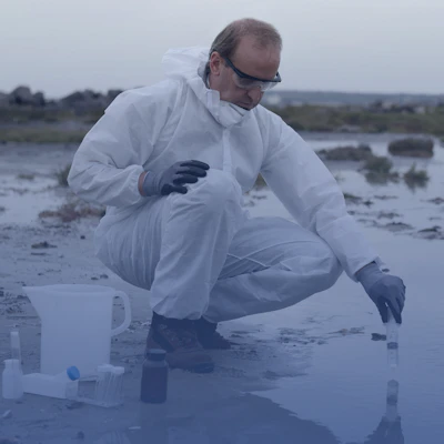 Scientist taking a sample from a puddle