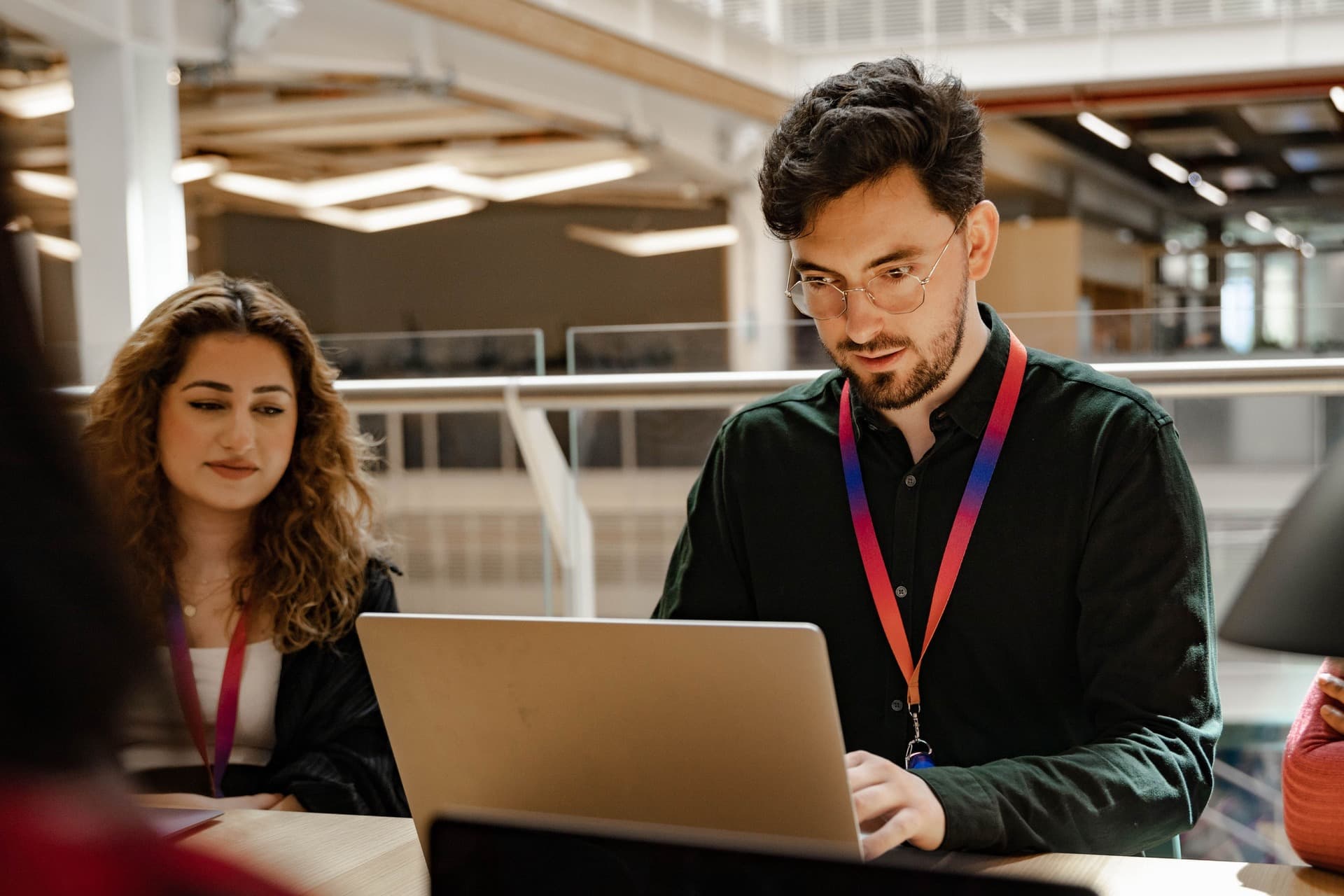 Two people concentrating on laptop.