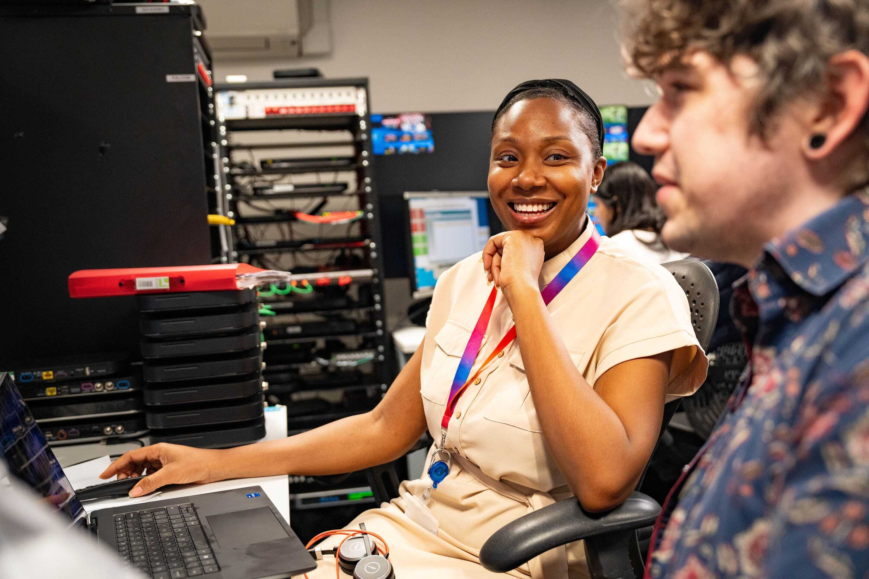 A woman at a desk smiling at a colleague