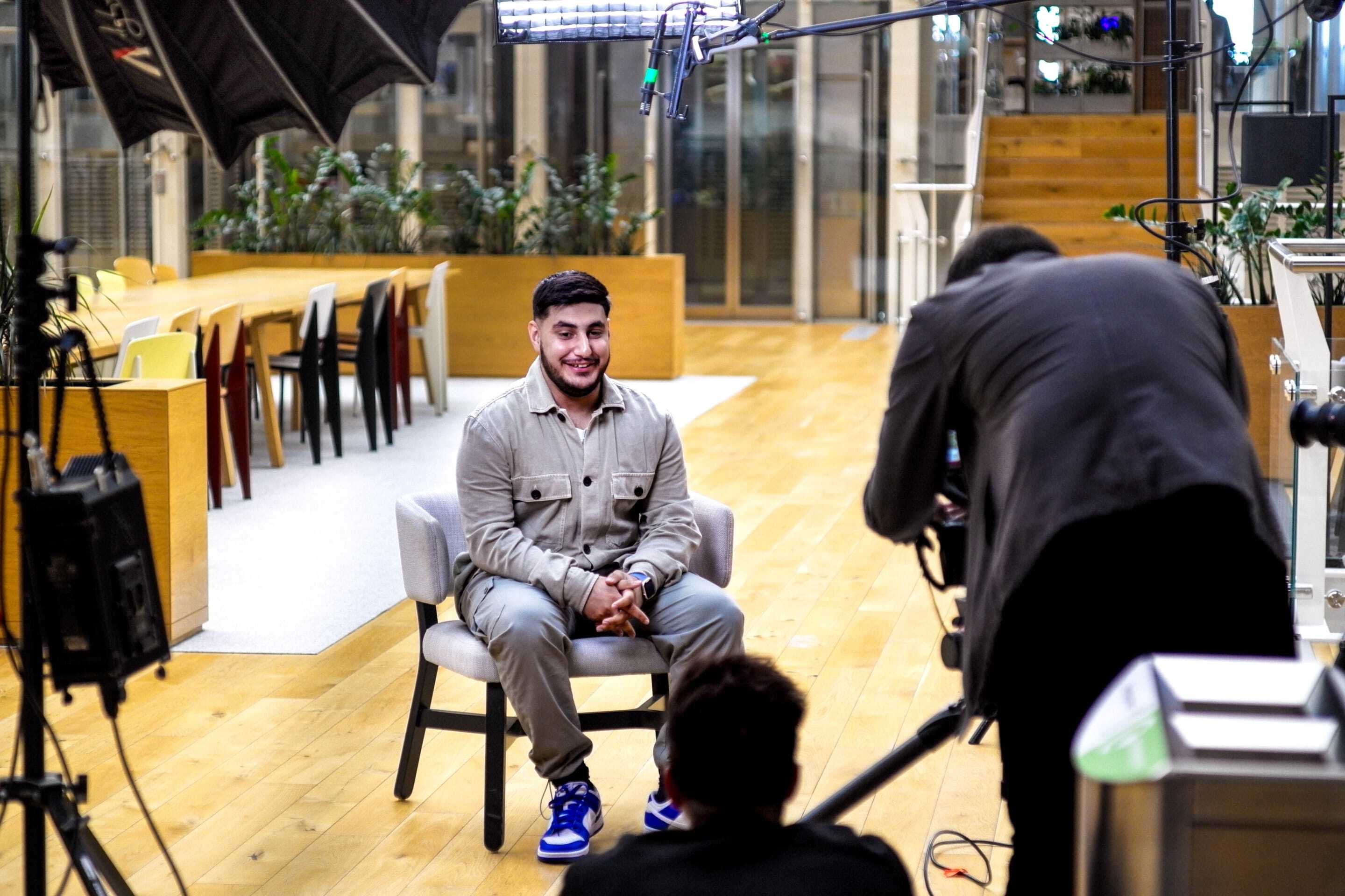 A man sitting in a chair in front of a camera crew
