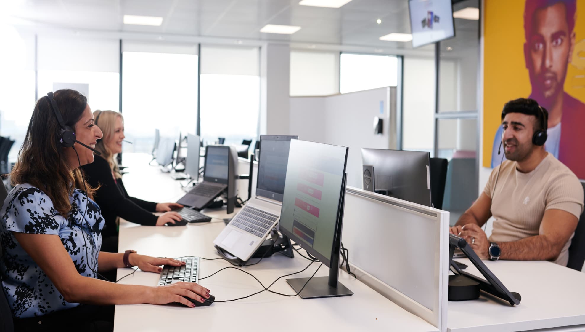 People wearing headsets smiling at a shared desk