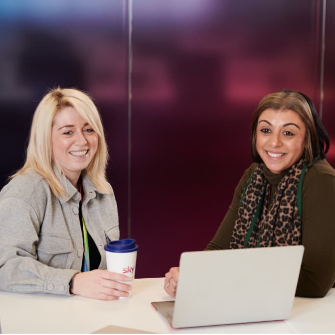 two women sitting next to each other smiling