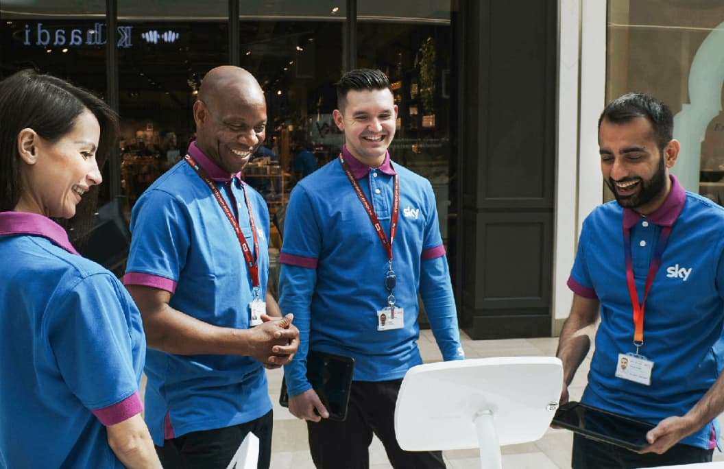 people smiling and gathered around a Sky product
