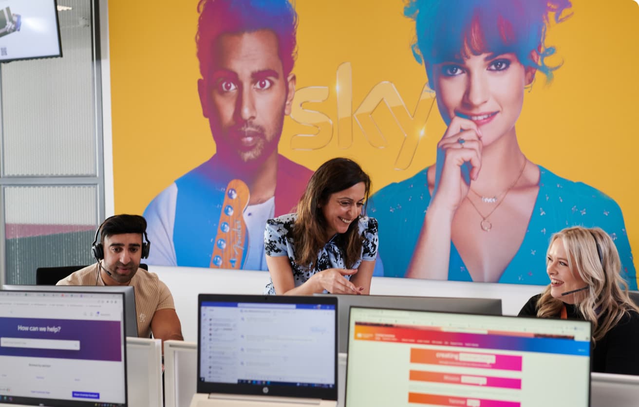 people wearing headsets and laughing with each other at a desk