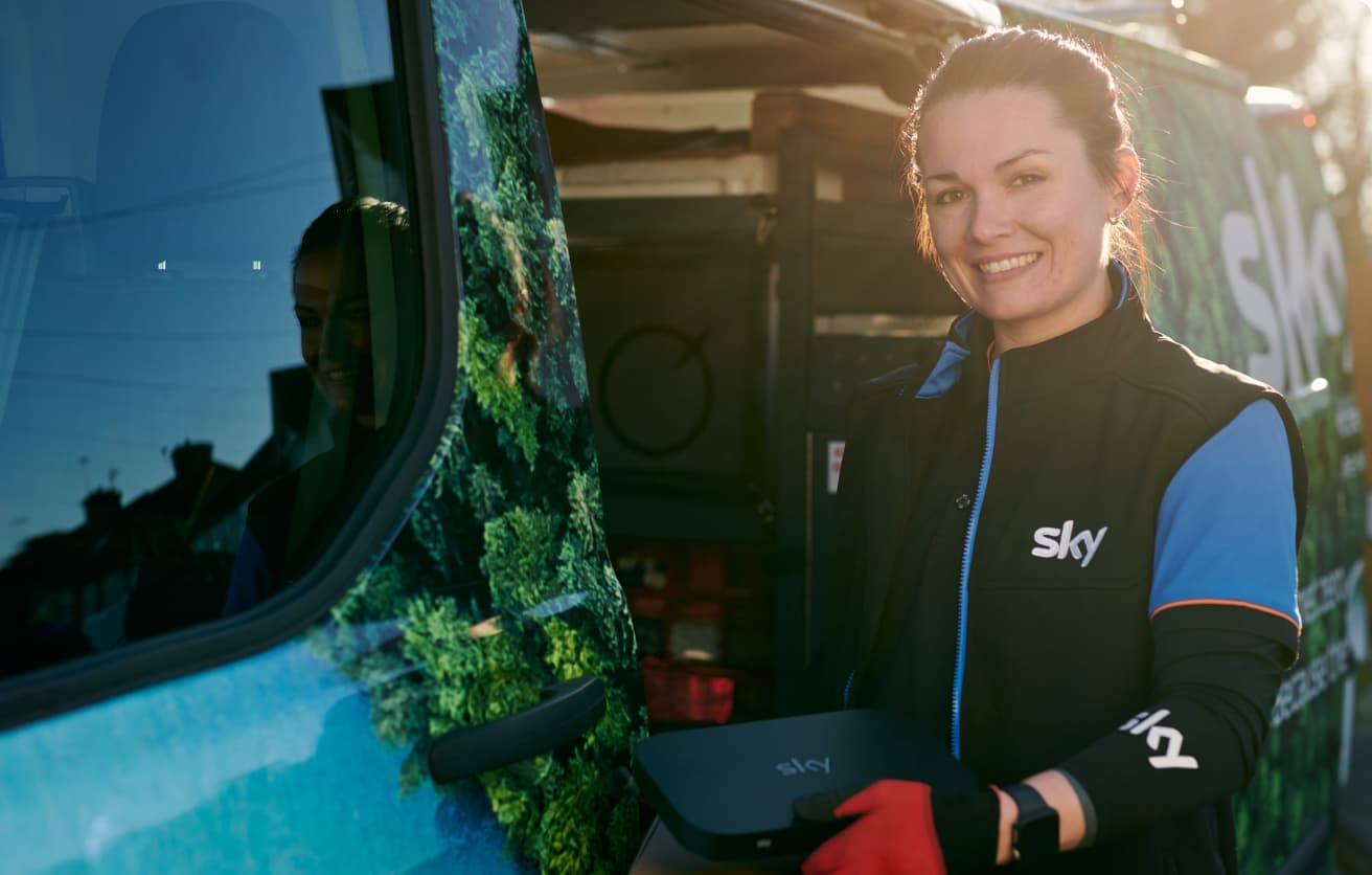 woman smiling and standing next to a Sky van