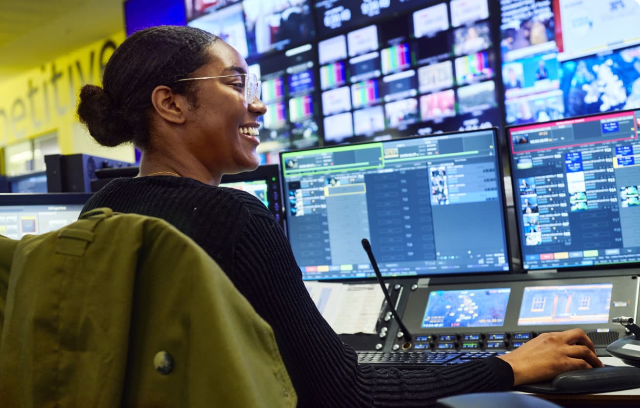 smiling woman in front of multiple screens